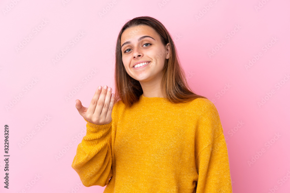 Teenager girl with yellow sweater over isolated pink background inviting to come with hand. Happy that you came Teenager girl with yellow sweater over isolated pink background inviting to come with hand. Happy that you came