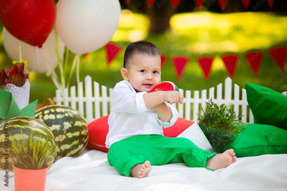 Obraz premium Laughing baby boy 1-2 year old eating watermelon outdoors. Summer party concept