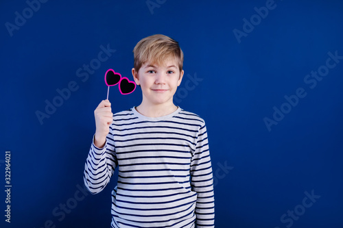 Birthday party and young boy with glasses in hats and props on blue background