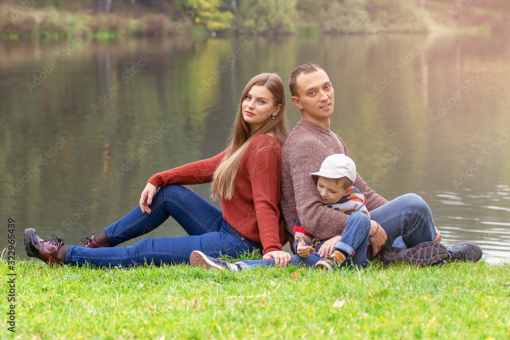 Happy family holding hands sitting on green lawn outdoor park, having quality time together. Happy family holding hands sitting on green lawn outdoor park, having quality time together.