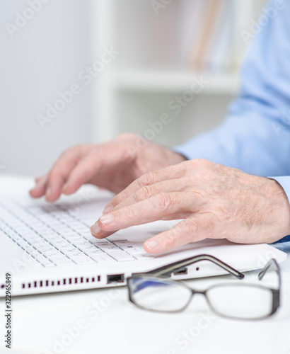 Close up hands of elderly person work on laptop computer in a office