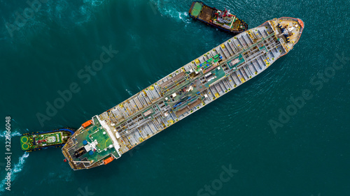 Aerial top view of fuel tanker ship at the port, Oil terminal is industrial facility for storage of oil and gas petrochemical products ready for transport to further storage facilities.