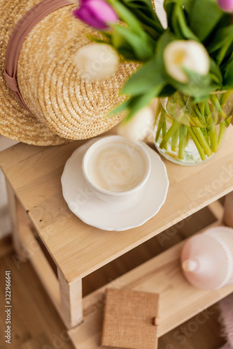 Women's things. Casket, women's straw hat, wicker bag, sweater, bouquet of tulips in a glass vase. Natural products. Cup of cappuccino.
