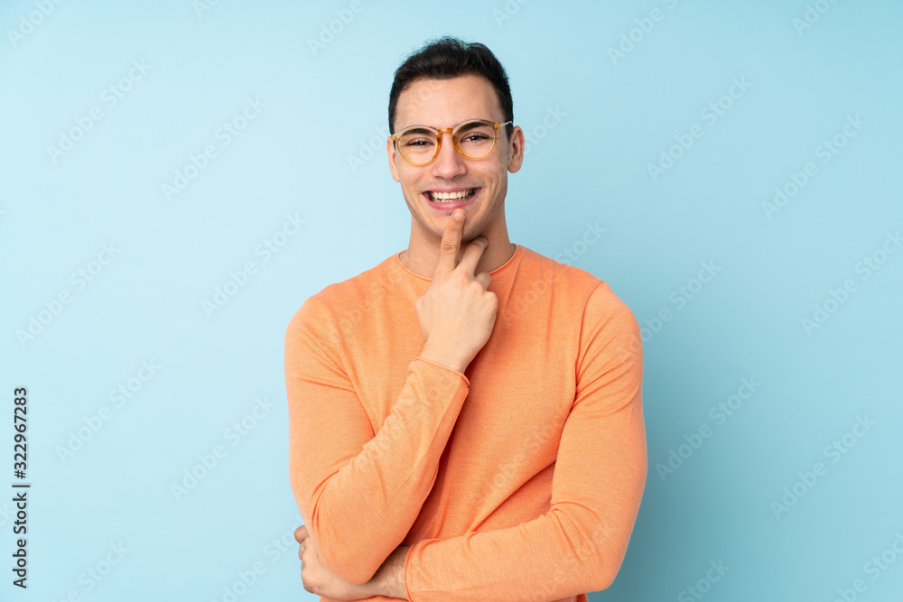 Young caucasian handsome man isolated on blue background with glasses and smiling Young caucasian handsome man isolated on blue background with glasses and smiling