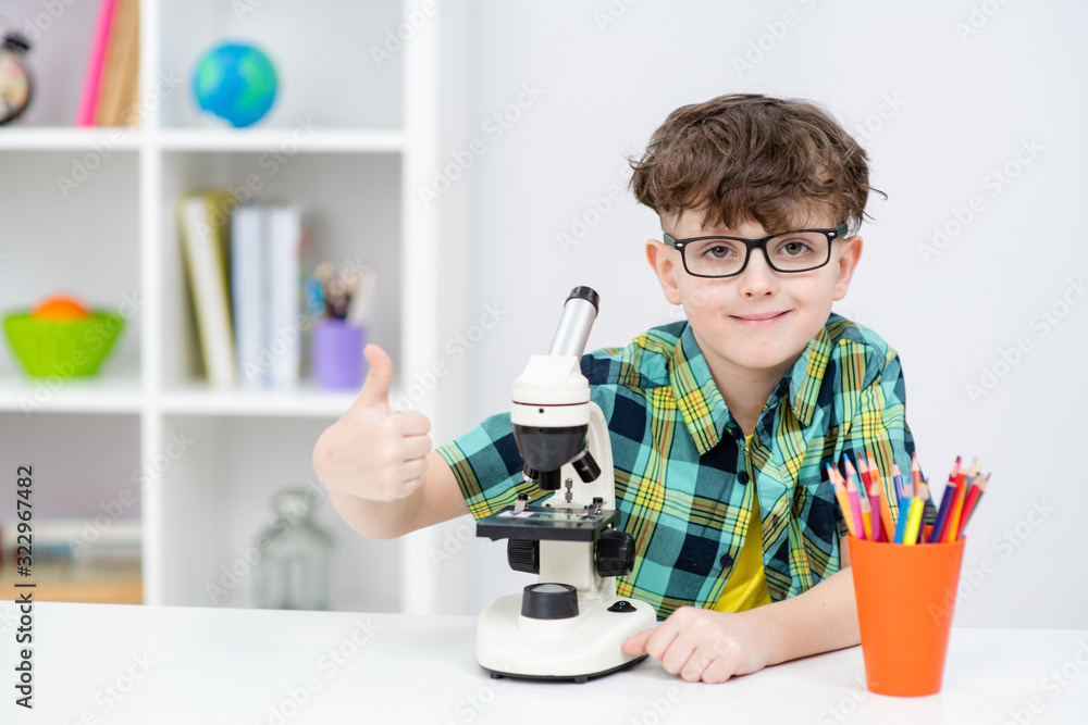 Young boy with microscope shows thumbs up gesture