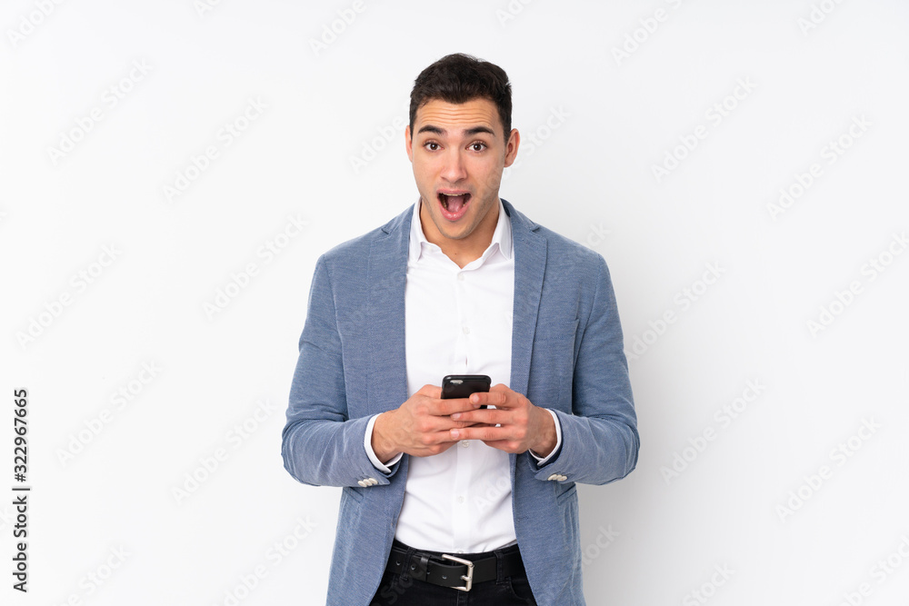 Young handsome businessman on isolated background surprised and sending a message Young handsome businessman on isolated background surprised and sending a message