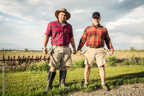 Portrait of farmers pulling out empty pockets after long day of work, father and son. Laurel, Montana, USA photo