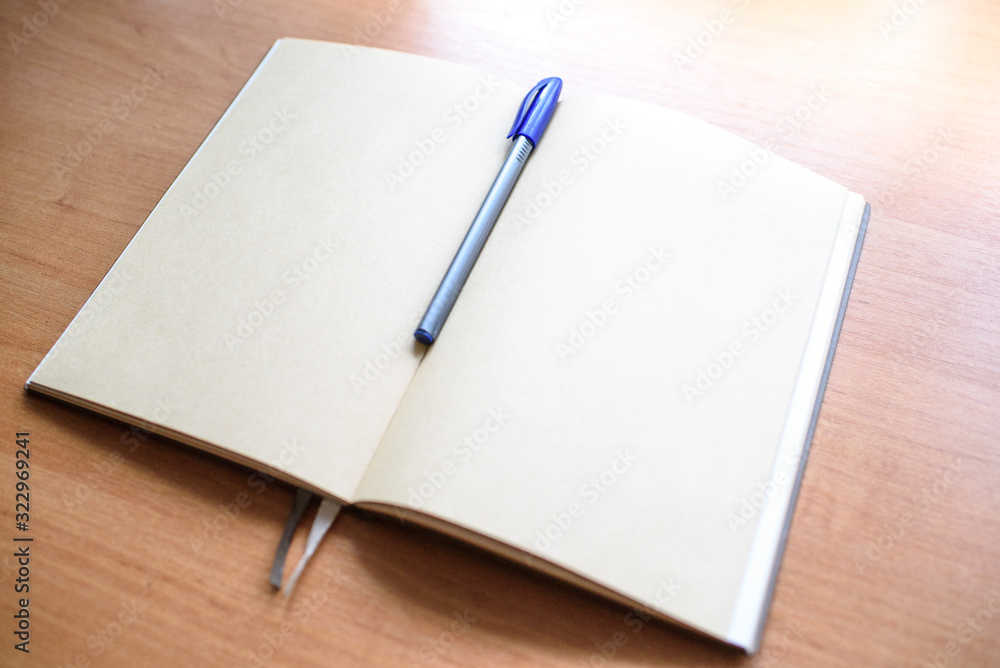 Notepad and pen on a light wooden table in the office. Notepad and pen on a light wooden table in the office.