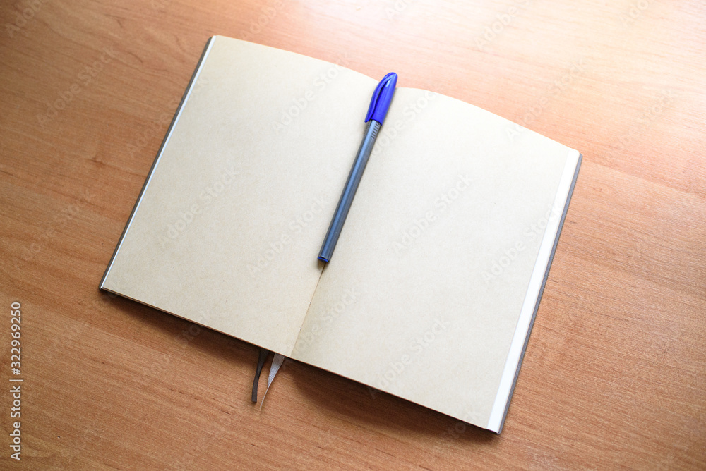 Notepad and pen on a light wooden table in the office. Notepad and pen on a light wooden table in the office.