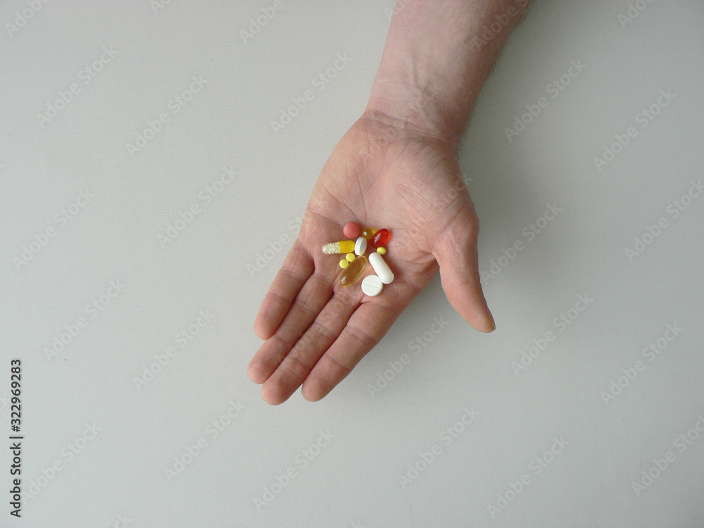 Colorful capsules and pills holds in hand a man. Influenza epidemic concept, vitamins for beauty, drug addiction treatment, healthcare, pharmacy. Treatment of diseases with medicines. Copy space. Colorful capsules and pills holds in hand a man. Influenza epidemic concept, vitamins for beauty, drug addiction treatment, healthcare, pharmacy. Treatment of diseases with medicines. Copy space.