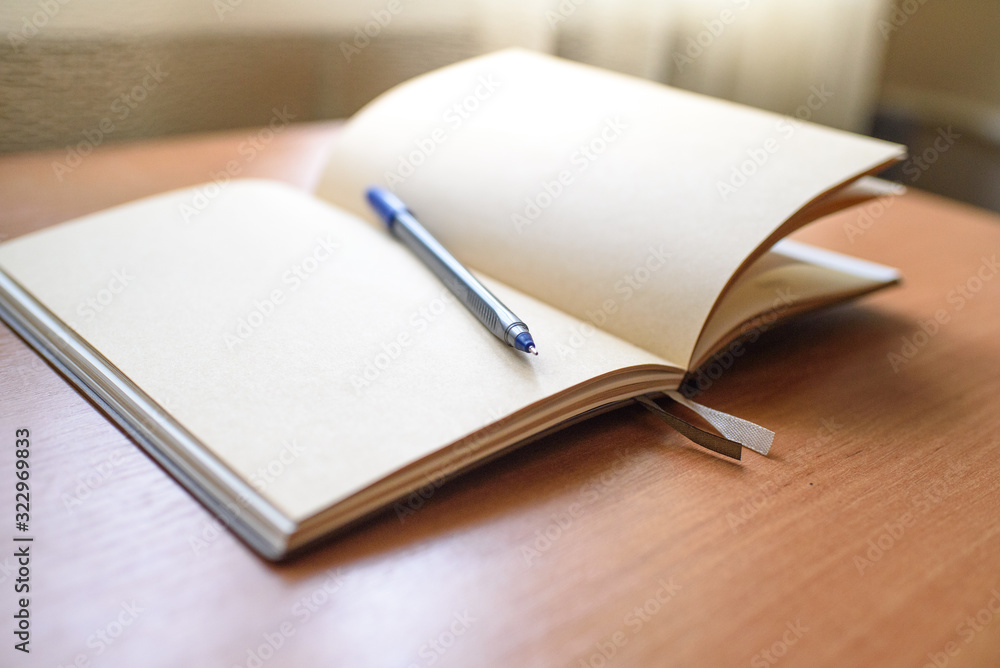 Notepad and pen on a light wooden table in the office. Notepad and pen on a light wooden table in the office.