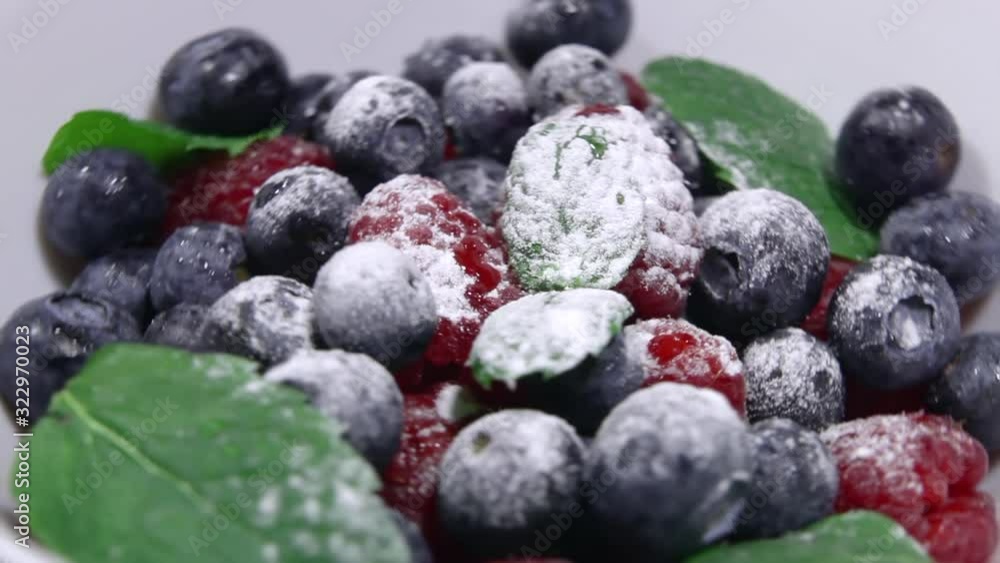 Blueberries in powdered sugar with mint leaves. Bio fruits, healthy eating, vegan food, diet. Fresh berries in a white bowl sprinkled with powdered sugar close-up. Blueberries in powdered sugar with mint leaves. Bio fruits, healthy eating, vegan food, diet. Fresh berries in a white bowl sprinkled with powdered sugar close-up.