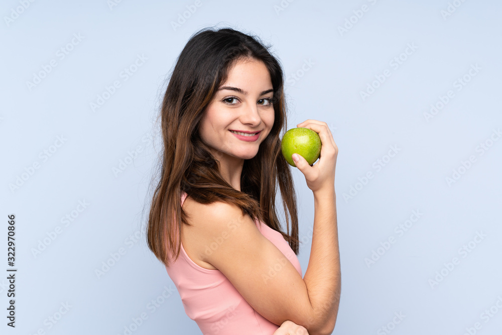 Young caucasian woman isolated on blue background eating an apple Young caucasian woman isolated on blue background eating an apple