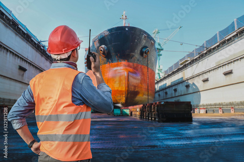 Photographie Engineer, forman in command repairing the old cargo ship in floating dry dock yard, Technician Industrial workers with walkie-talkie operation control in shipyard