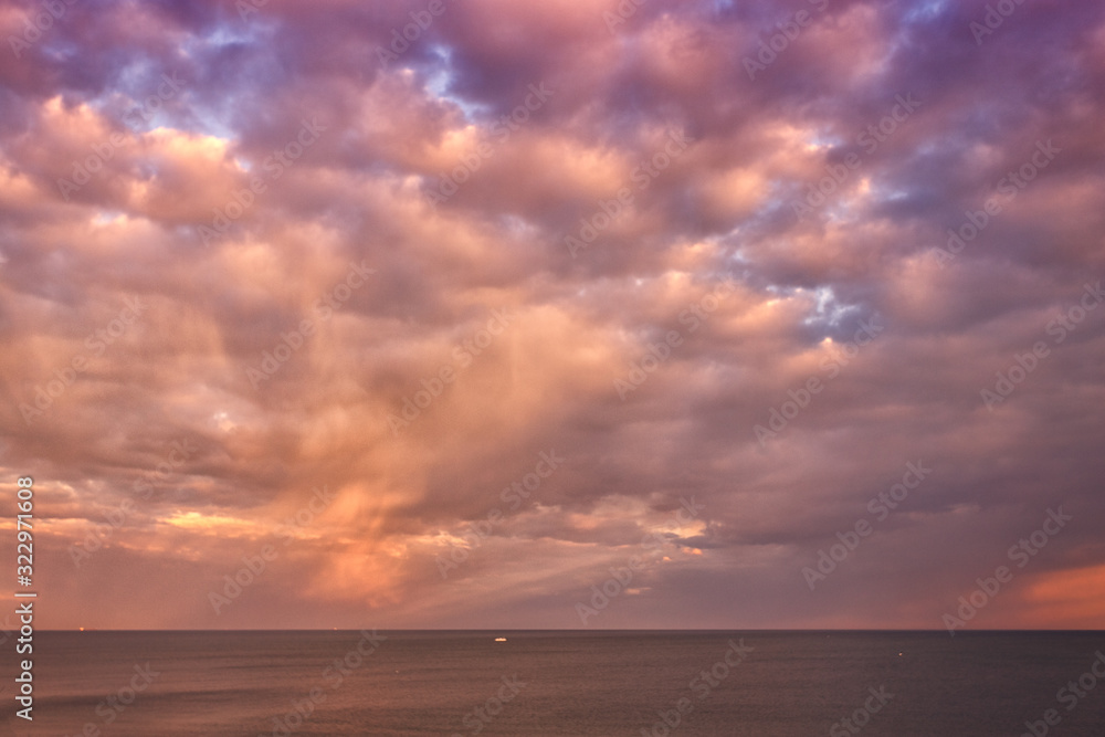 Beautiful sunrise, sunset at sea. Red, gray, pink, yellow clouds. The dark blue sky, the sea.