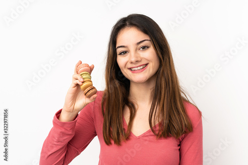 Young caucasian woman isolated on pink background holding colorful French macarons and smiling a lot