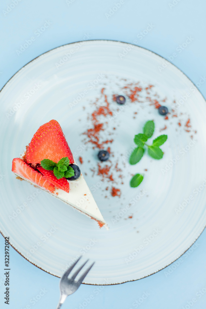 A beautiful piece of cake with berries with butter cream on a blue background. Cake with red cakes. A beautiful piece of cake with berries with butter cream on a blue background. Cake with red cakes.
