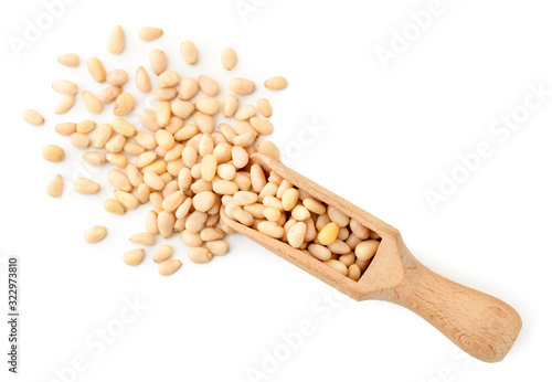 Pine nuts spilled from a wooden scoop on a white background. The view of top.