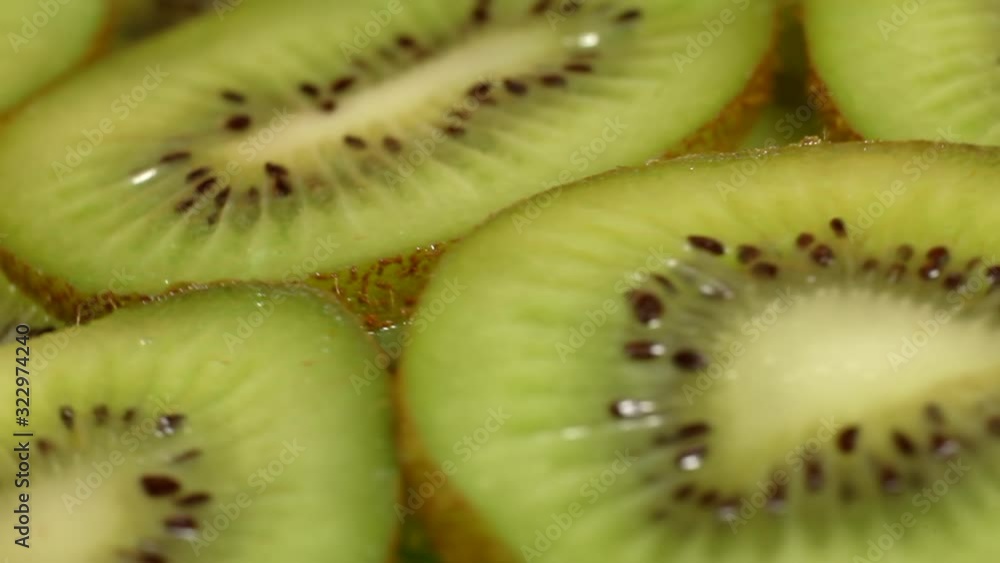 Fresh kiwi revolve in a circle on a wooden board on an orange background. Kiwi close-up shot of kiwis on a wooden bench, in slow motion. Fresh kiwi revolve in a circle on a wooden board on an orange background. Kiwi close-up shot of kiwis on a wooden bench, in slow motion.