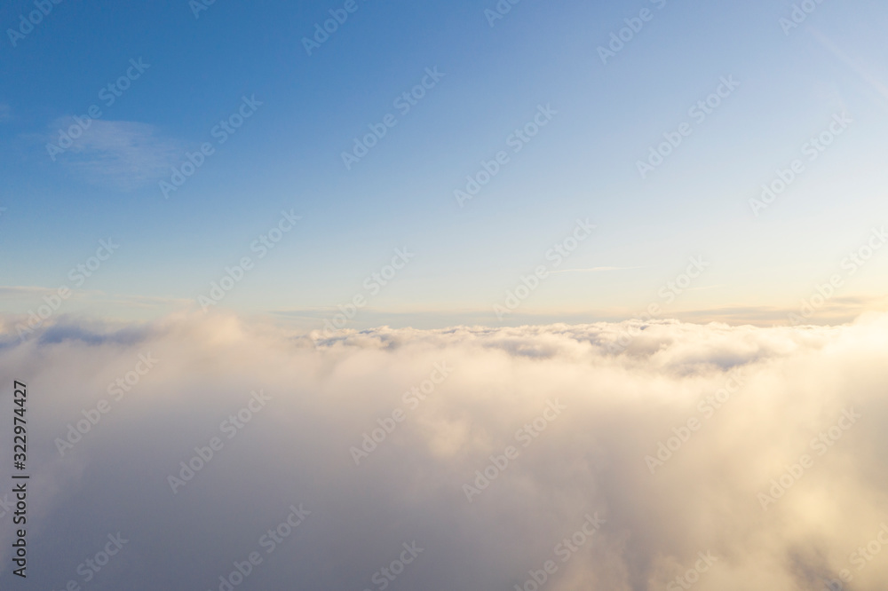 Aerial view White clouds in blue sky. Top fly. Looking from the drone. Aerial bird's eye view. Aerial top view cloudscape. Texture of clouds. View from above. Sunrise or sunset over clouds
