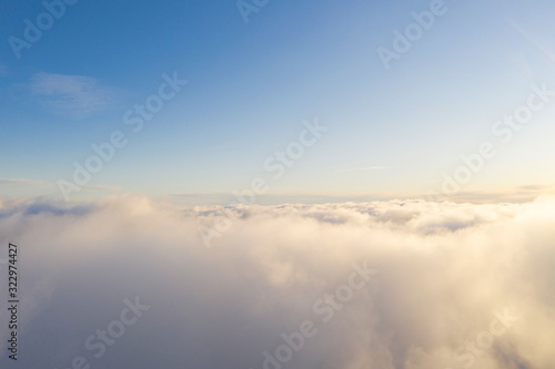 Aerial view White clouds in blue sky. Top fly. Looking from the drone. Aerial bird s eye view. Aerial top view cloudscape. Texture of clouds. View from above. Sunrise or sunset over clouds