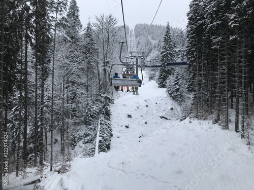 Chair lift in the winter for skiers. Cableway in the mountains with skiers. Snowy forest in the Carpathians, skiing. Winter climb to the mountains in the forest.