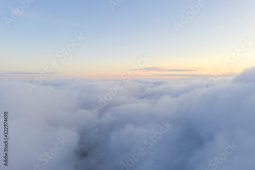 Aerial view White clouds in blue sky. Top fly. Looking from the drone. Aerial bird's eye view. Aerial top view cloudscape. Texture of clouds. View from above. Sunrise or sunset over clouds