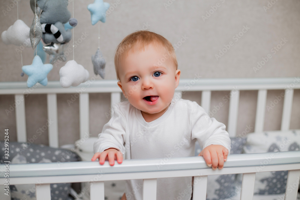 healthy baby in white clothes is sitting in a child's bed healthy baby in white clothes is sitting in a child's bed