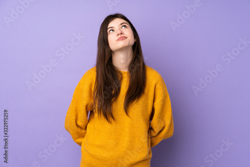 Young Ukrainian teenager girl over isolated purple background and looking up