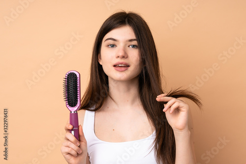 Young Ukrainian teenager girl over isolated background with hair comb