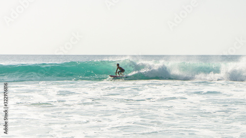 Photography View of a silhouette of a boy surfin' the waves at sunset in Bali, Indonesie