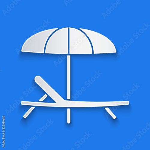 Paper cut Sunbed icon isolated on blue background. Beach umbrella and Sun lounger. Paper art style. Vector Illustration
