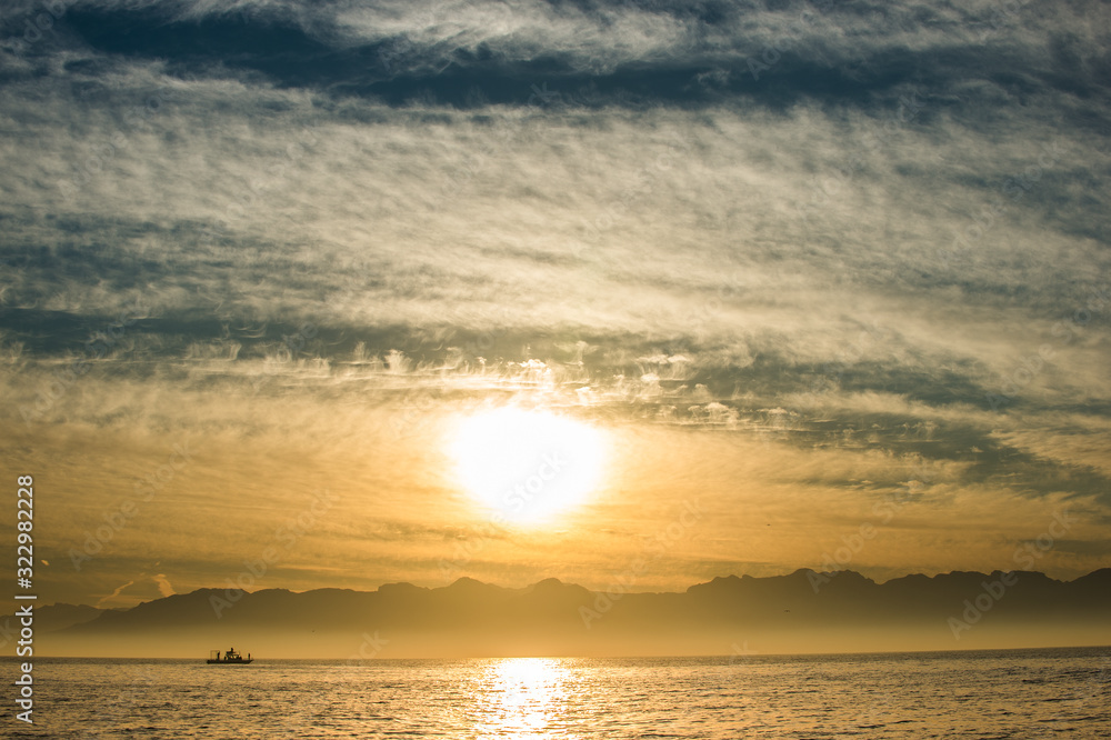 Naklejka premium Silhouette of Speed boat in the ocean at sunset. oating at sunset in Atlantic ocean, South Africa