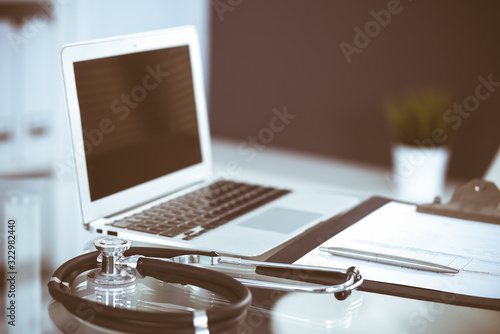 Stethoscope, prescription medical form lying on glass table with laptop computer. Medicine or pharmacy concept. Medical tools at doctor working table