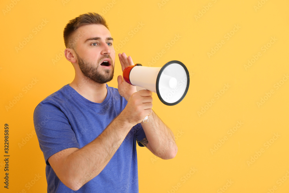 Emotional young man with megaphone on color background Emotional young man with megaphone on color background