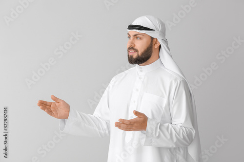 Obraz na plátně Handsome Arab man showing something on grey background