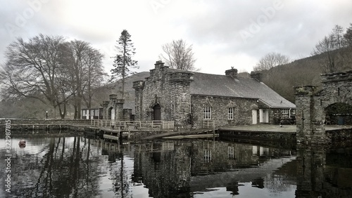 Sunrise over a lake in England, behind the sky is cloudy and there are mood swings. The club is in the foreground from a model with hills, trees on the other side of the lake.