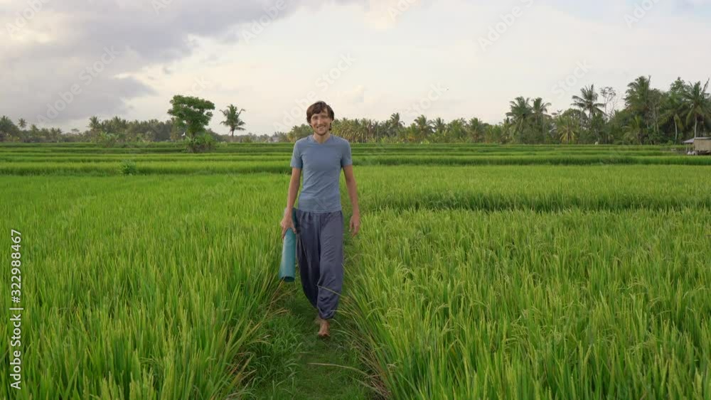 A young man has a yoga training on a beautiful rice field. Travel to Asia concept A young man has a yoga training on a beautiful rice field. Travel to Asia concept