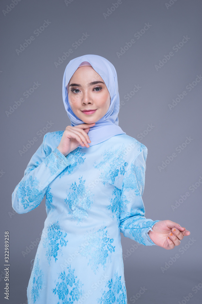 Beautiful Muslim female model wearing pastel blue modern kurung with hijab, a urban lifestyle apparel for Muslim women isolated on grey background. Beauty and hijab fashion concept. Half length Beautiful Muslim female model wearing pastel blue modern kurung with hijab, a urban lifestyle apparel for Muslim women isolated on grey background. Beauty and hijab fashion concept. Half length