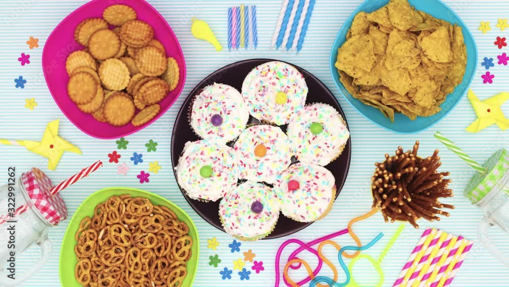 Cup cakes for birthday party move in circle on table with party food and decorations - Stop motion Cup cakes for birthday party move in circle on table with party food and decorations - Stop motion
