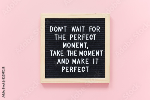 Don't wait for the perfect moment, take the moment and make it perfect. Motivational quote on black letter board frame on pink background. Concept inspirational quote of the day.