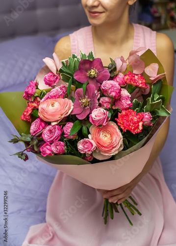 Woman holding a beautiful bouquet of large purple roses in a kraft paper.
