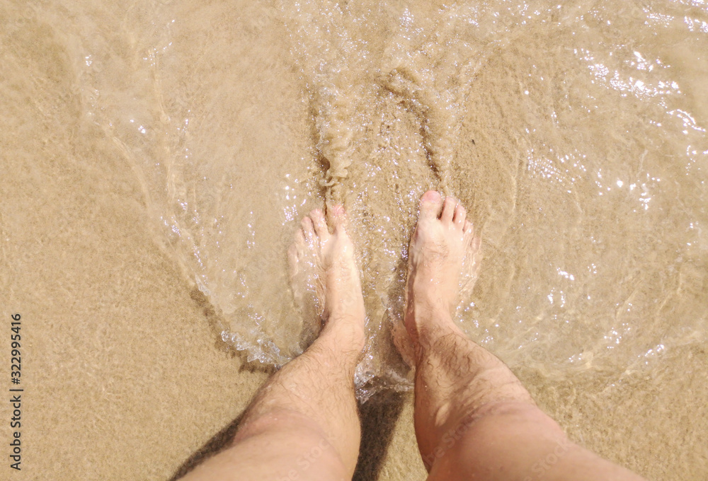 Feet of a man in the hot sand of the desert Feet of a man in the hot sand of the desert