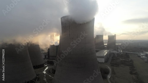 Aerial view overlooking power station cooling towers, Sunrise reveal through smoke steam emissions.