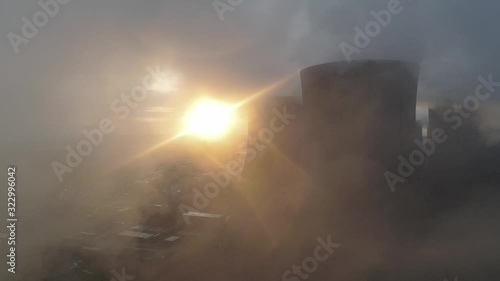 Aerial view of UK power station cooling towers smoke steam emissions. Glowing sunrise horizon burning.
