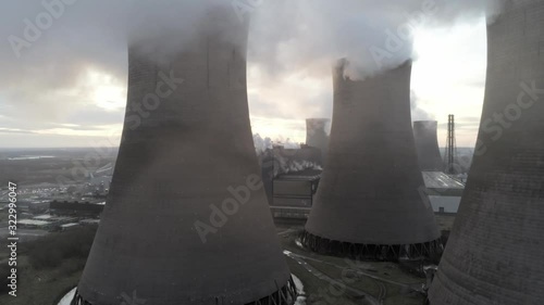 Aerial dolly right view of UK power station cooling towers smoke steam emissions, sunrise reveal behind chimney,