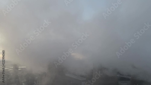 Aerial view of UK power station cooling towers overlooking smoke steam emissions at sunrise.