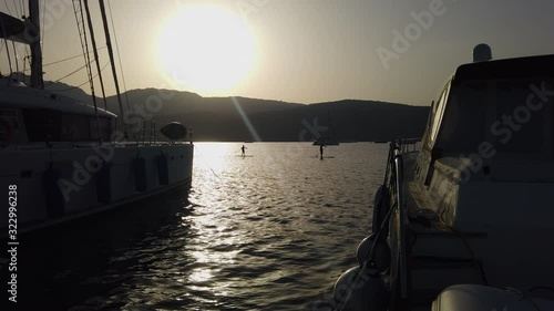 Wallpaper Mural People on standup paddleboard paddle between two boats at anchor during sunset Torontodigital.ca