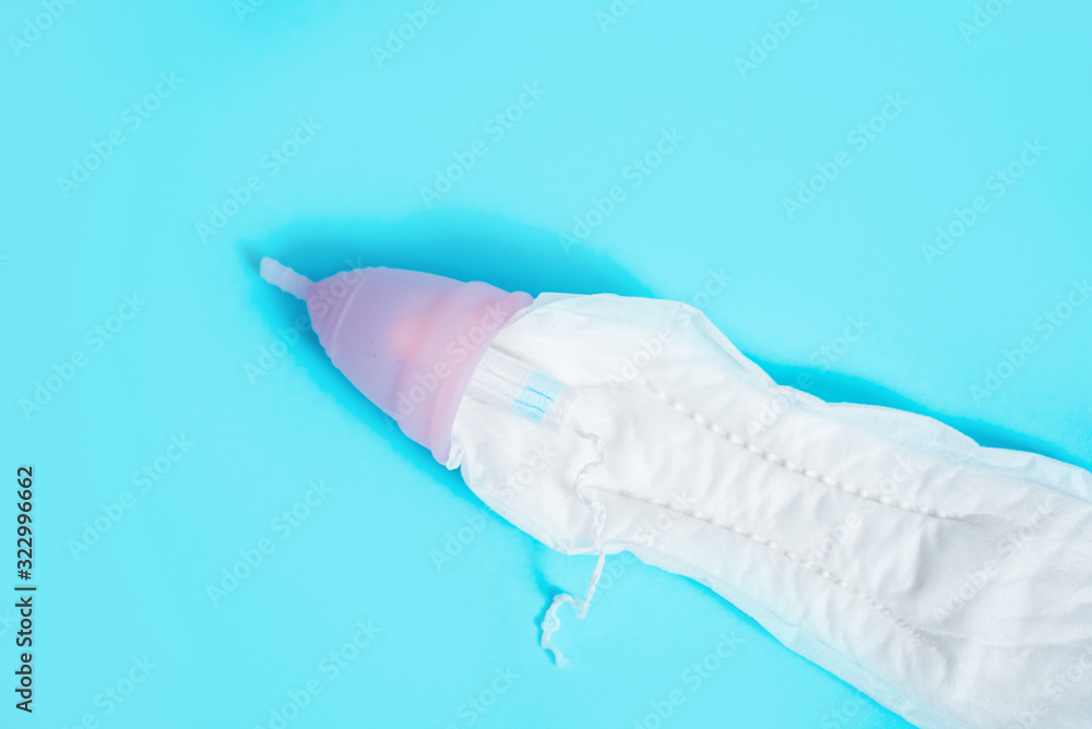 Fototapeta premium Feminine intimate hygiene set over blue background. Sanitary pad, swab or cup. the choice of a modern woman.Red rose. menstrual cycle concept in women