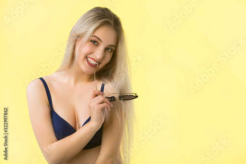 beautiful young woman in a swimsuit on a yellow background